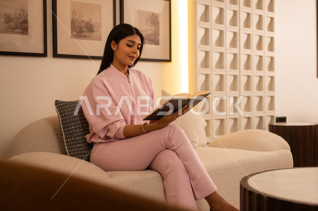 امرأة عربية تقرأ كتاباً على الأريكة في المنزل