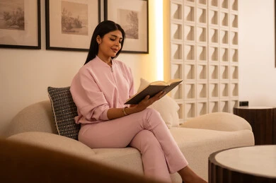 Arab Woman Reading a Book on a Sofa Indoors