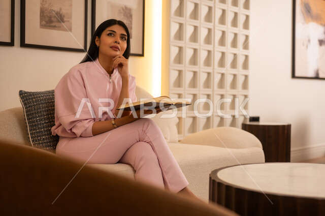 Arab Woman Reading Book on Sofa in Modern Interior