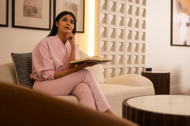 امرأة عربية تقرأ كتاباً على الأريكة في غرفة حديثة