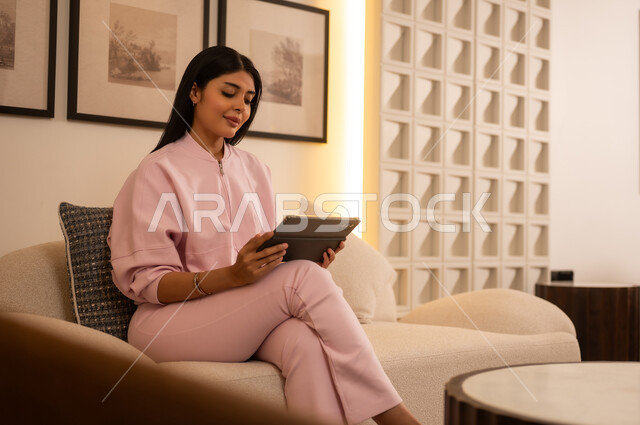Woman in Pink Outfit Using Tablet on Sofa