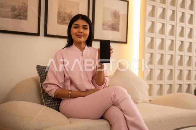 امرأة سعودية تحمل هاتف ذكي بشاشة فارغة في الداخل