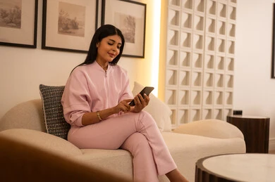 امرأة عربية تستخدم الهاتف الذكي في غرفة معيشة حديثة