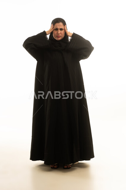 امرأة سعودية بالعباءة السوداء تعاني من الصداع والتوتر