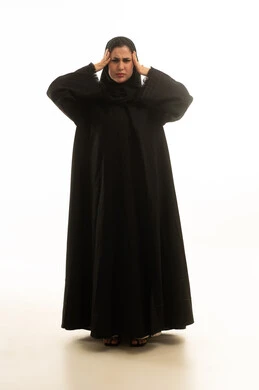 امرأة سعودية بالعباءة السوداء تعاني من الصداع والتوتر