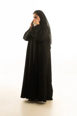 امرأة سعودية مريضة ترتدي عباءة وتمسك منديلاً