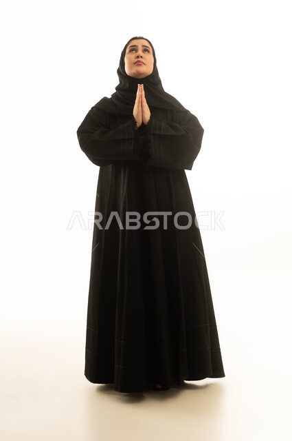 امرأة سعودية بالعباءة السوداء في وضعية الدعاء