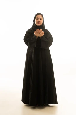 امرأة سعودية بالعباءة السوداء تدعو على خلفية بيضاء