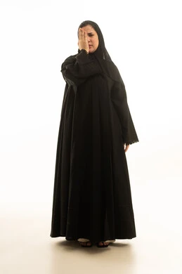 امرأة سعودية بالعباءة السوداء تعاني من ألم في العين