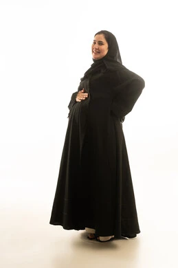 امرأة سعودية حامل بالعباءة السوداء على خلفية بيضاء