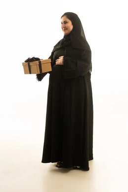 امرأة سعودية حامل تحمل صندوق هدايا بخلفية بيضاء