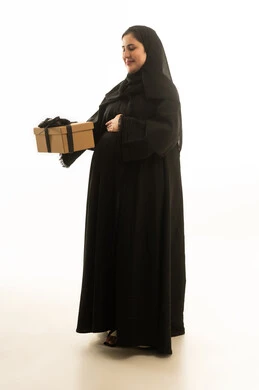 امرأة سعودية حامل بالعباءة السوداء تحمل هدية