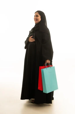 امرأة سعودية حامل مع حقائب تسوق بخلفية بيضاء