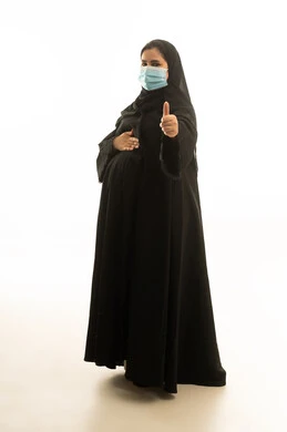 امرأة سعودية حامل ترتدي كمامة مع علامة الرضا