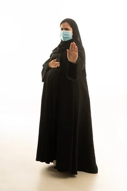 امرأة سعودية حامل بالعباءة والكمامة تشير بالتوقف