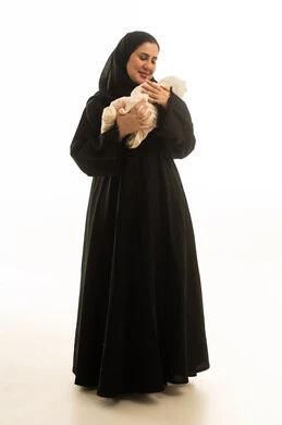 امرأة سعودية بالعباءة تحمل طفلاً حديث الولادة في الاستوديو