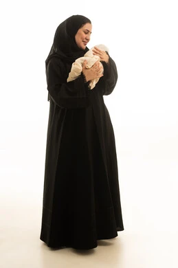 أم سعودية بالعباءة السوداء تحمل طفلها الرضيع