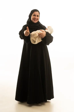 امرأة سعودية بالعباءة تحمل مولوداً جديداً