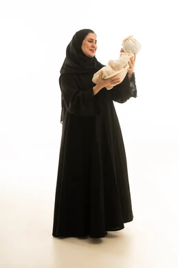 أم إماراتية تحمل مولوداً جديداً بخلفية بيضاء