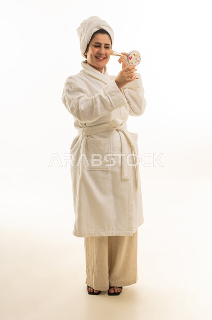 امرأة عربية برداء حمام أبيض تضع المكياج