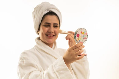 امرأة سعودية برداء الحمام تضع المكياج أمام المرآة امرأة سعودية برداء الحمام تضع المكياج أمام المرآة