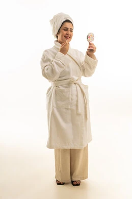 امرأة سعودية برداء حمام أبيض تضع أحمر الشفاه