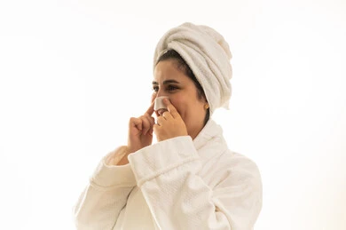 امرأة عربية برداء حمام تضع لاصقة تنظيف مسام الأنف