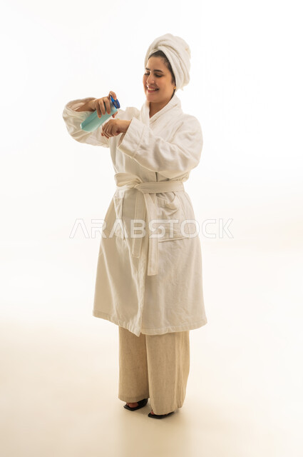 Saudi Woman in White Bathrobe Applying Skin Lotion