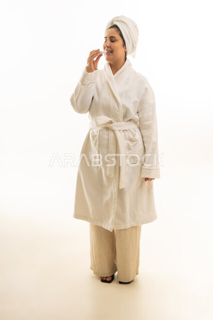 امرأة عربية برداء حمام أبيض تضع مرطب شفاه