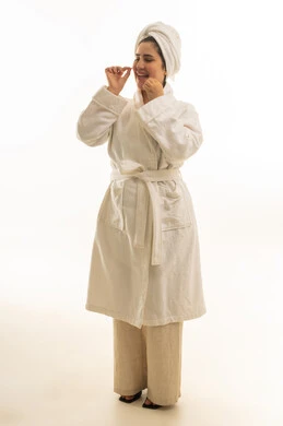 امرأة عربية برداء الحمام تنظف أسنانها بالخيط