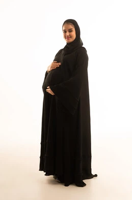 امرأة سعودية حامل بالعباءة السوداء بخلفية بيضاء