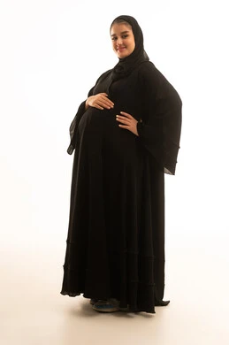 امرأة سعودية حامل بالعباءة السوداء بخلفية بيضاء