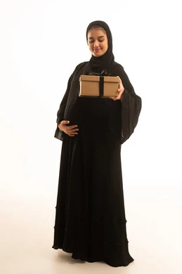امرأة سعودية حامل تحمل صندوق هدايا بخلفية بيضاء