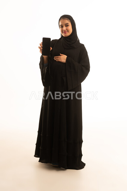 امرأة سعودية حامل مع هاتف ذكي بخلفية بيضاء