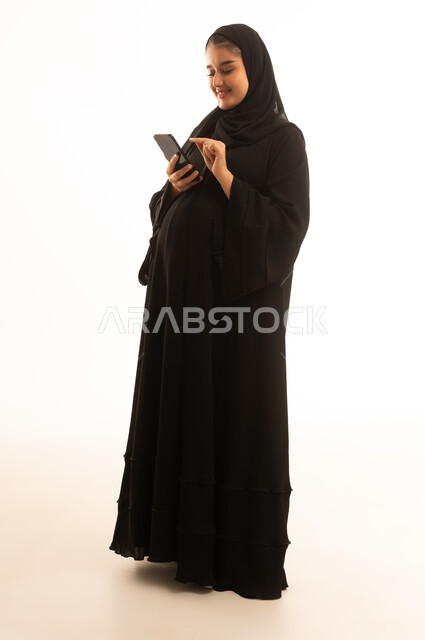 امرأة سعودية حامل تستخدم الجوال على خلفية بيضاء
