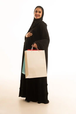 امرأة سعودية بالعباءة السوداء تحمل حقائب تسوق