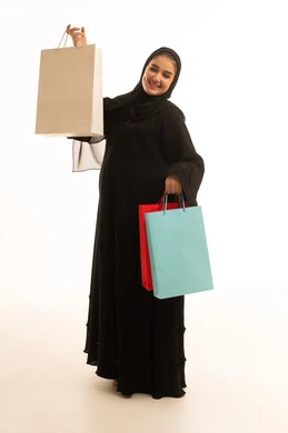 امرأة سعودية تحمل حقائب تسوق بخلفية بيضاء