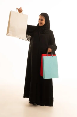 امرأة سعودية بعباءة سوداء تحمل أكياس تسوق ملونة