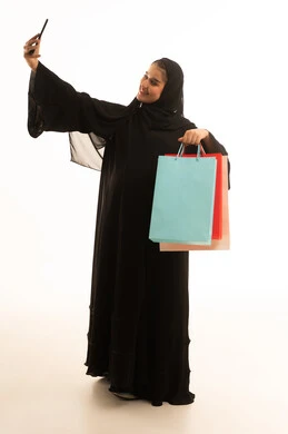 امرأة سعودية تحمل حقائب تسوق تلتقط سيلفي