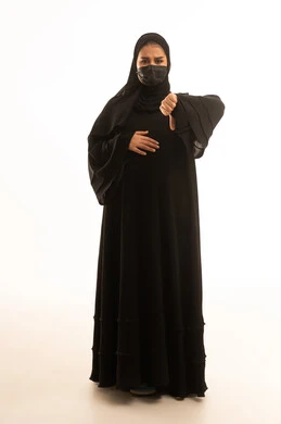 امرأة سعودية حامل تشير بعدم الإعجاب بخلفية بيضاء