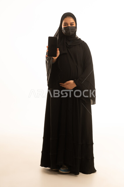 Pregnant Saudi Woman in Abaya with Smartphone