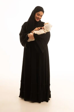 أم سعودية بالعباءة السوداء تحمل طفل رضيع