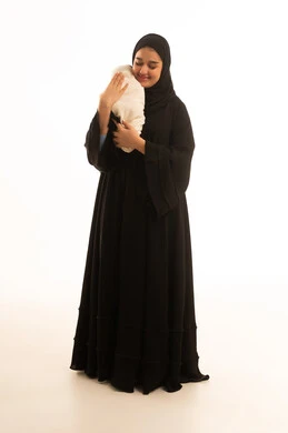 أم سعودية تحتضن مولوداً جديداً بخلفية بيضاء