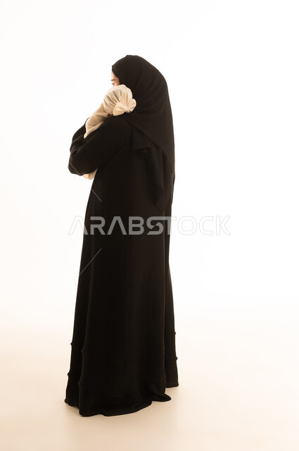 أم سعودية تحمل طفلاً رضيعاً على خلفية بيضاء