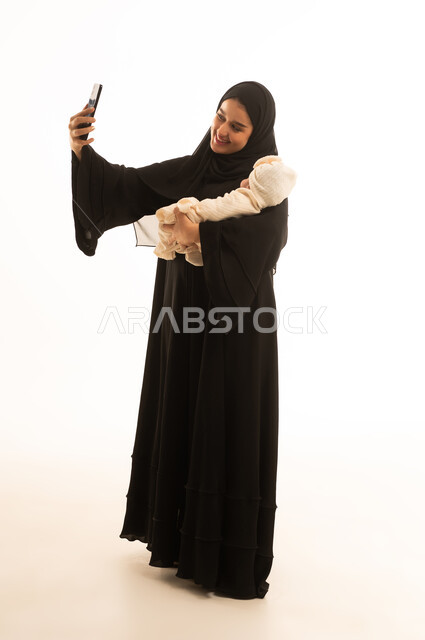 امرأة سعودية تلتقط سيلفي مع طفلها الرضيع في الاستوديو