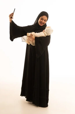 امرأة سعودية بالعباءة تلتقط سيلفي مع طفلها الرضيع