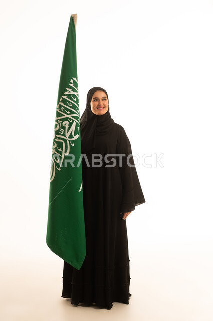 امرأة سعودية مع العلم الوطني في استوديو بخلفية بيضاء
