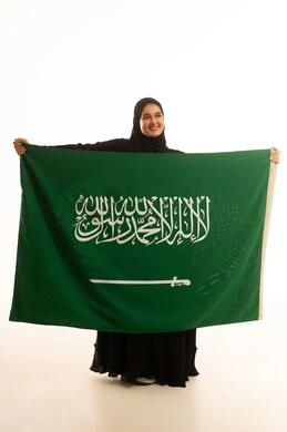 امرأة سعودية تحمل العلم الوطني على خلفية بيضاء