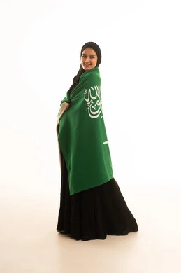 امرأة سعودية بالعباءة تحمل علم المملكة العربية السعودية