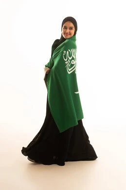 Saudi Woman in Abaya Wrapped in Saudi Flag on White Background
